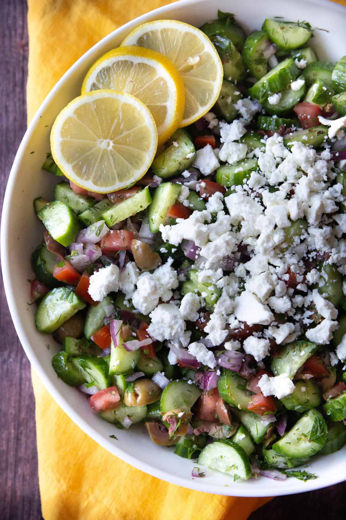 Refreshing Mediterranean Cucumber Salad a top view of Mediterranean cucumber salad topped with crumbled feta and served with lemon wedges
