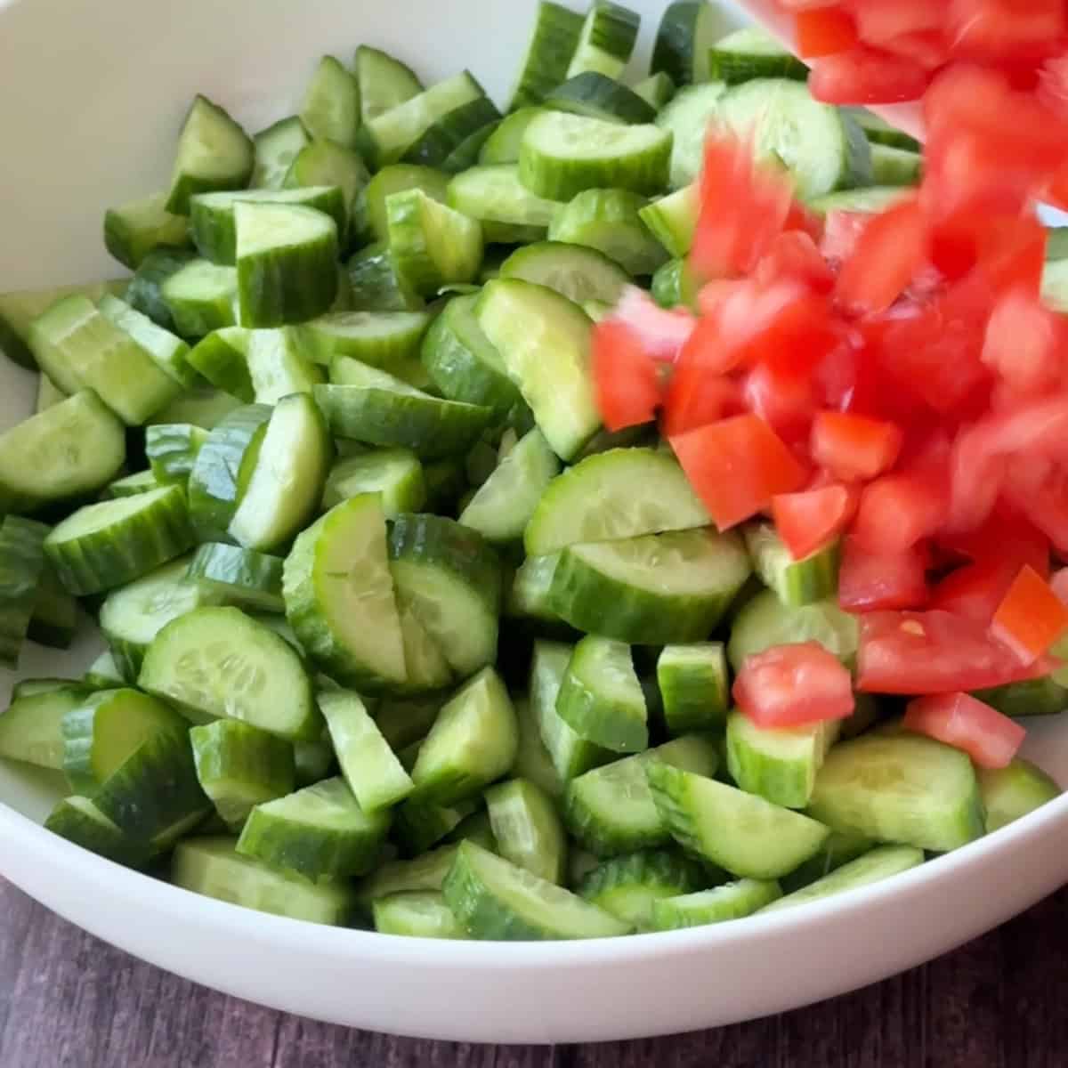 How to Make Mediterranean Cucumber Salad a bowl of chopped Persian cucumbers and Roma tomatoes