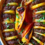 Close-up of a Turkish-inspired baked meatball and potato dish, with tender meatballs nestled between slices of soft, roasted potatoes.