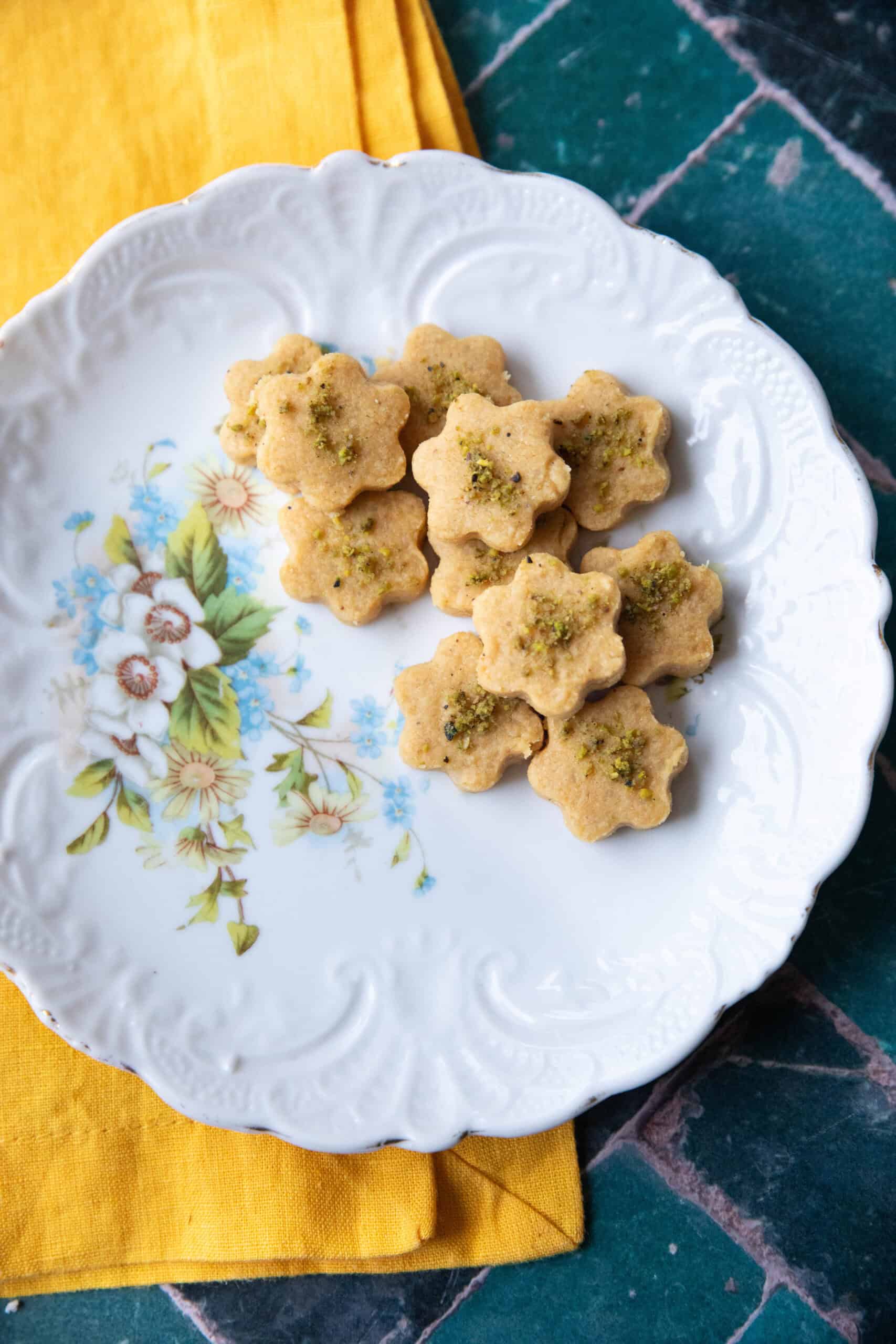 A plate of freshly baked Nan-e Nokhodchi cookies with a soft, crumbly texture and a hint of pistachio topping.