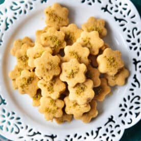 A batch of homemade Persian chickpea cookies resting on a white plate, ready to be enjoyed with tea.
