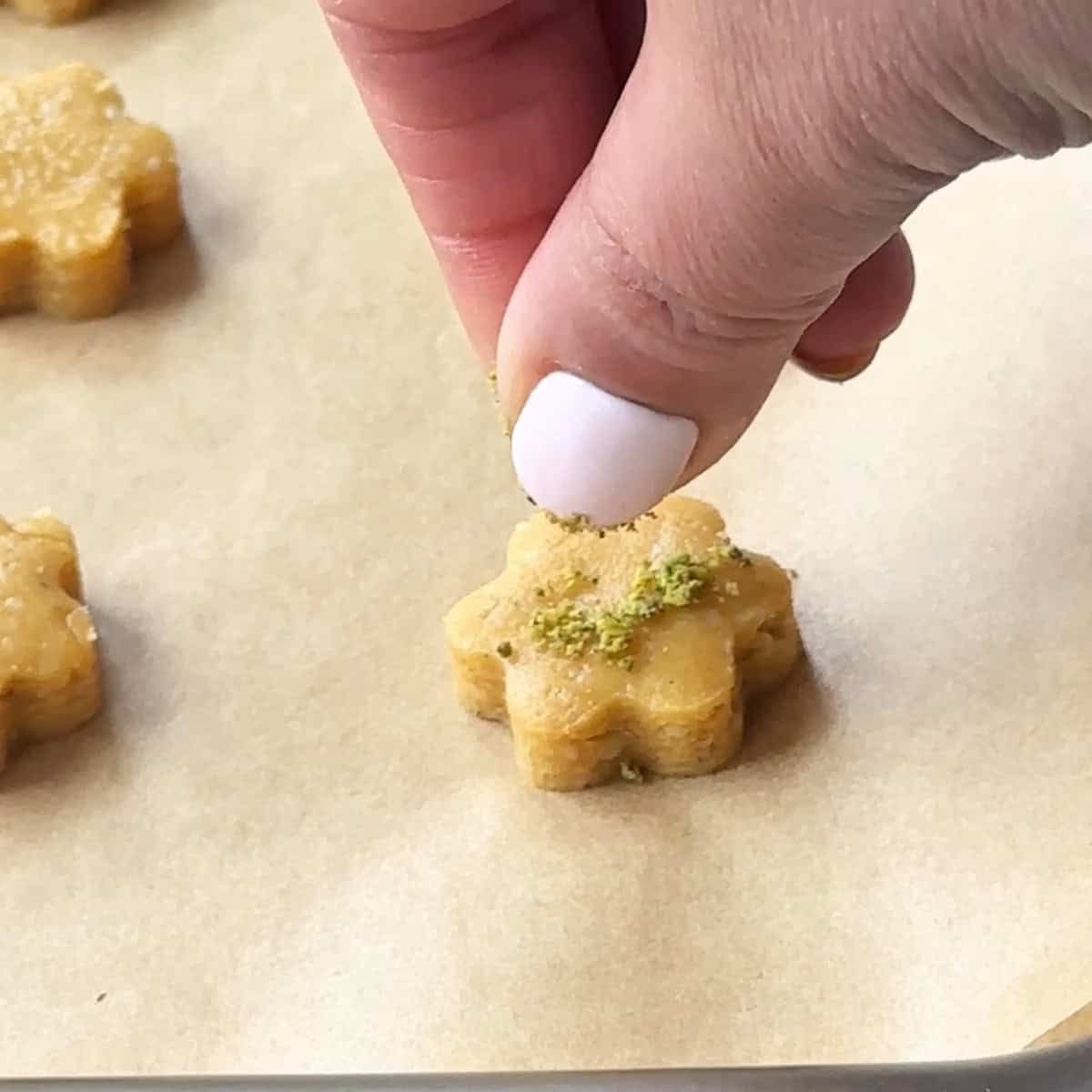 Nokhodchi Cookies sprinkling some ground pistachios on the nokhodchi cookies before baking