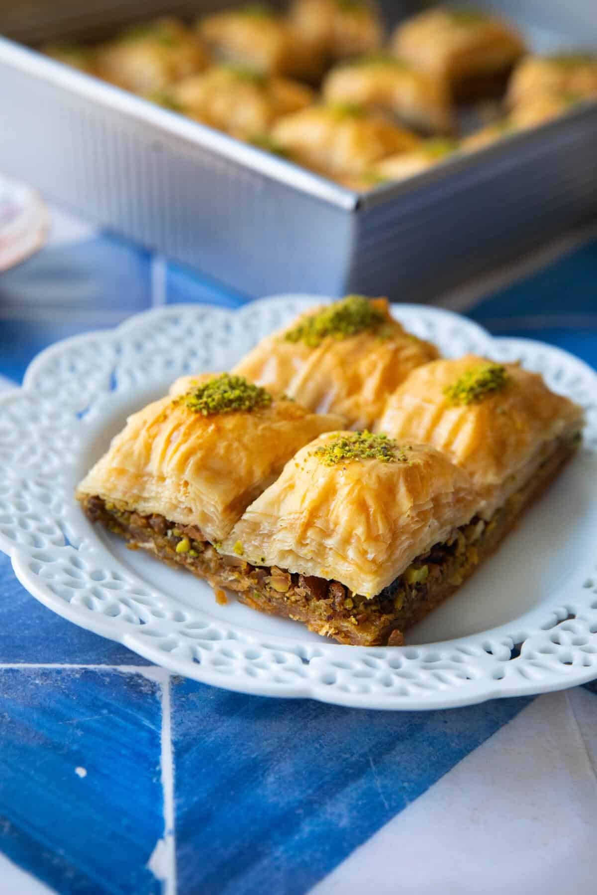 Pistachio Baklava Recipe 4 pieces of pistachio baklava served in a decorative white plate with their pistachio filling clearly visible