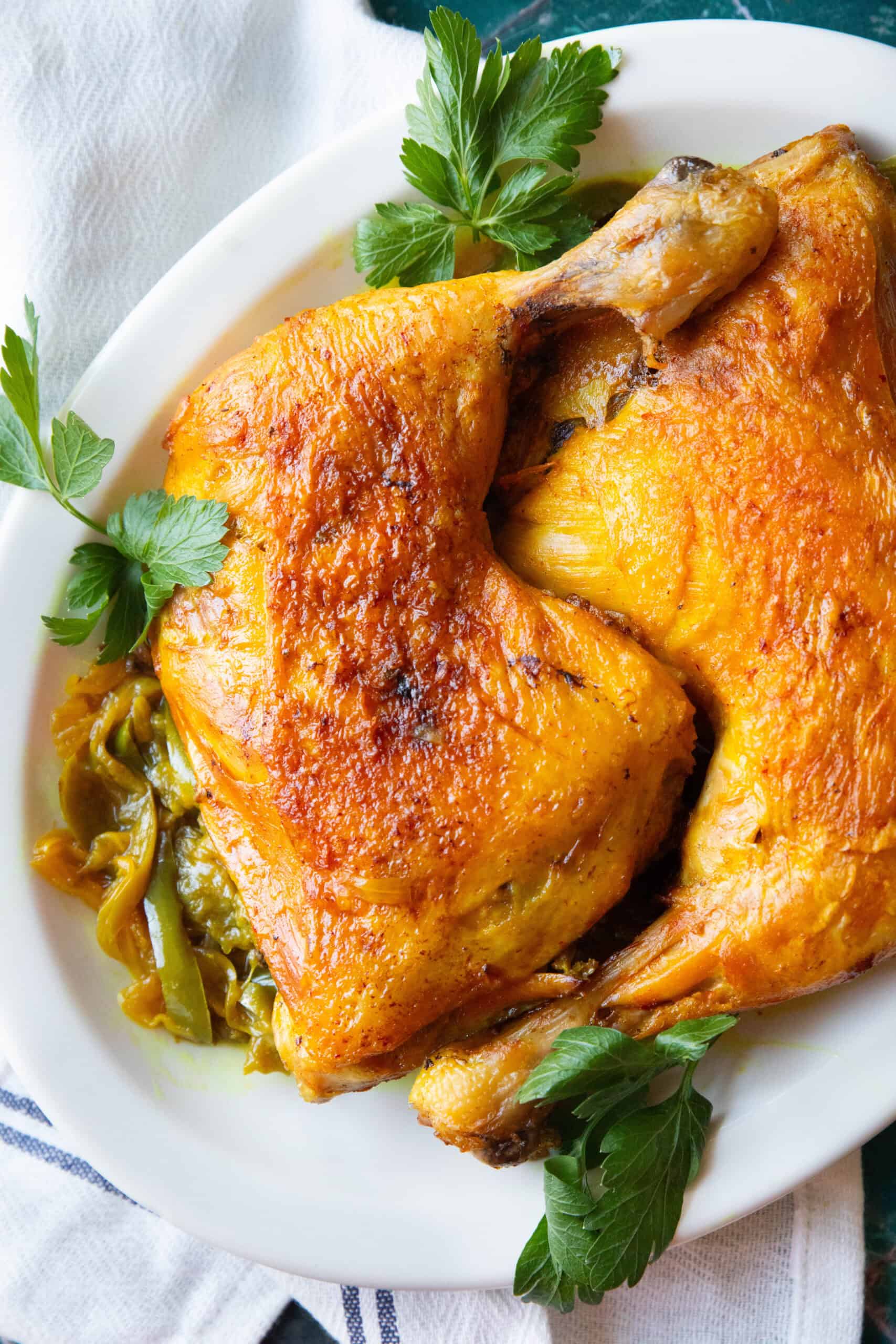 a shot of Persian saffron chicken with crispy golden skin served on a large platter with sauteed sliced onion and green blee pepper