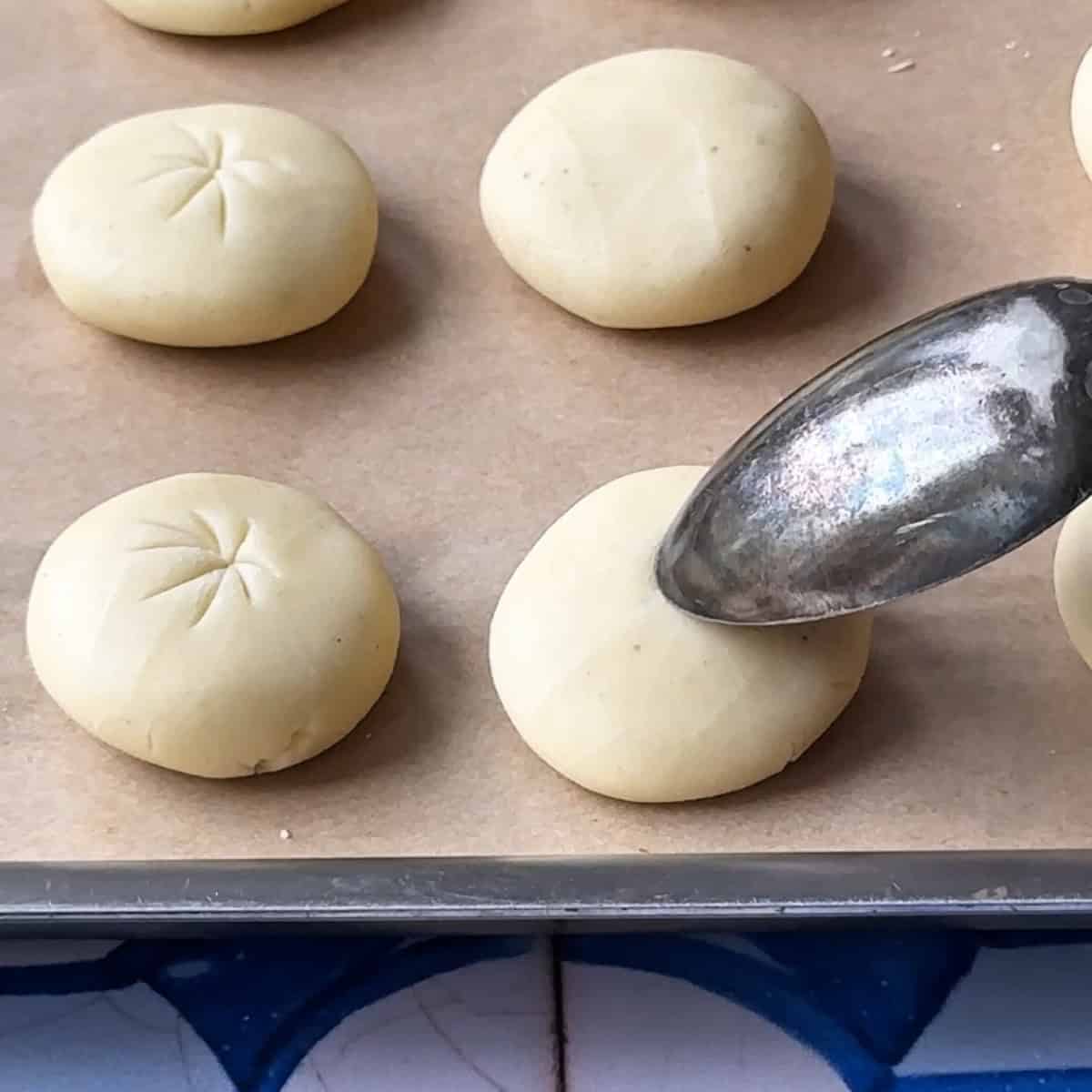 creating light indentations on the surface of cookies using the edge of a spoon