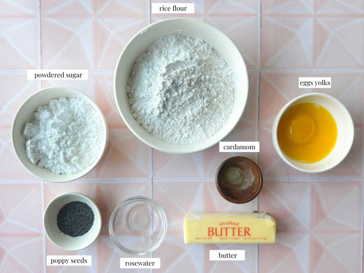 Nan-e Berenji Ingredients top shot of Nan-e Berenji ingredients: rice flour, powdered sugar, butter, eggs yolks, cardamom, rosewater, and poppy seeds