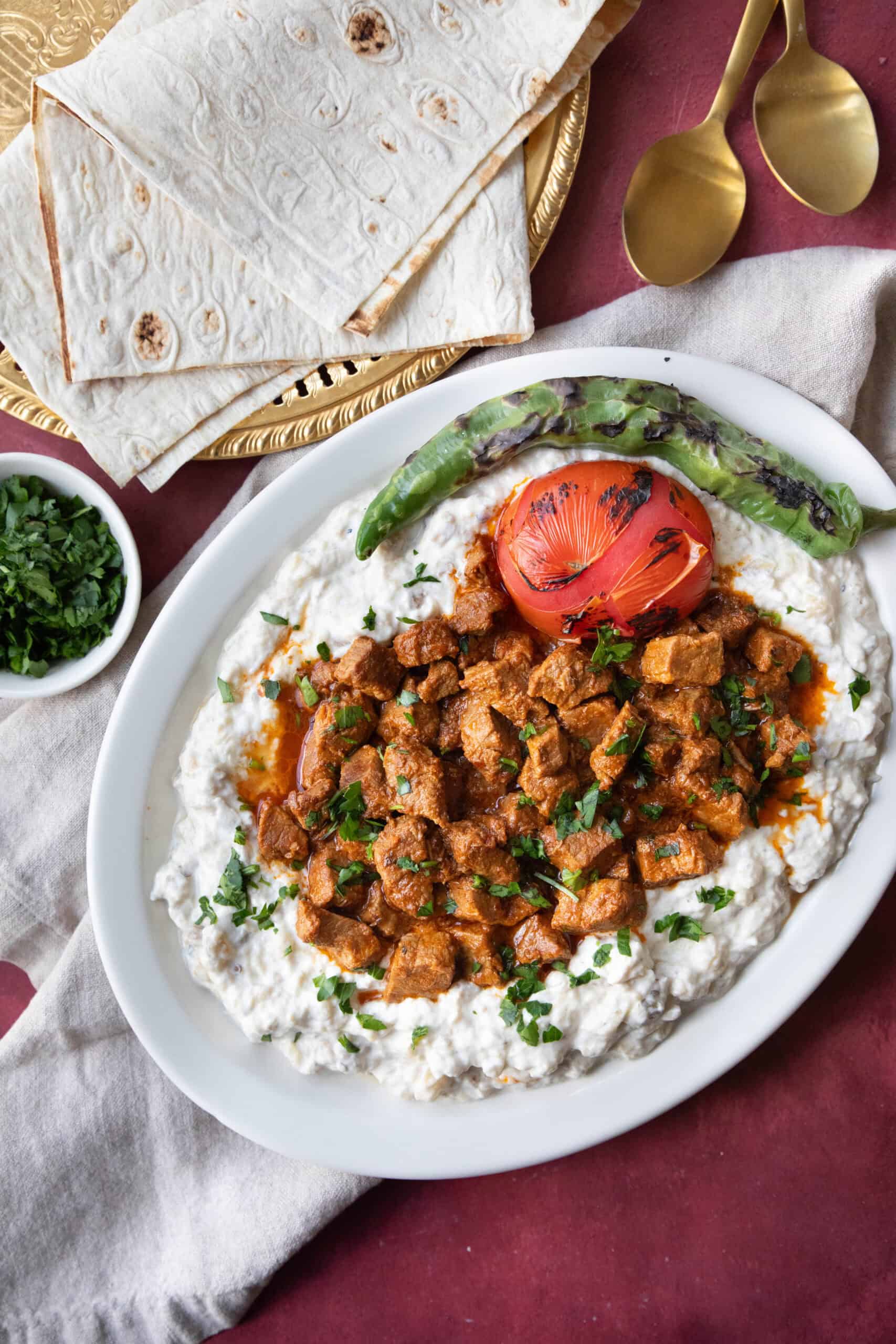 Ali Nazik Recipe Ali Nazik plated with a layer of creamy yogurt and smoked eggplant, topped with spiced lamb and chopped parsley.