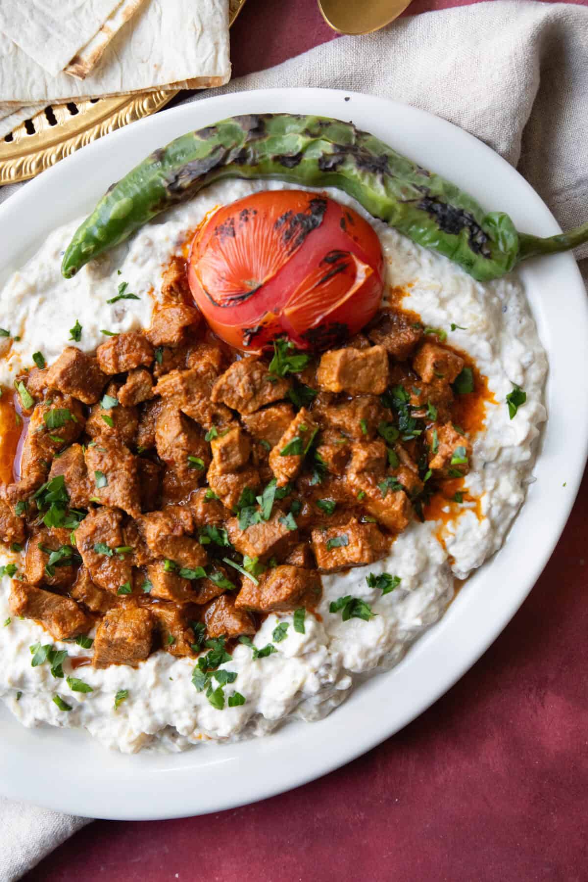 Traditional Ali Nazik Rich, spiced beef stew layered over smoky eggplant and yogurt purée, garnished with parsley.