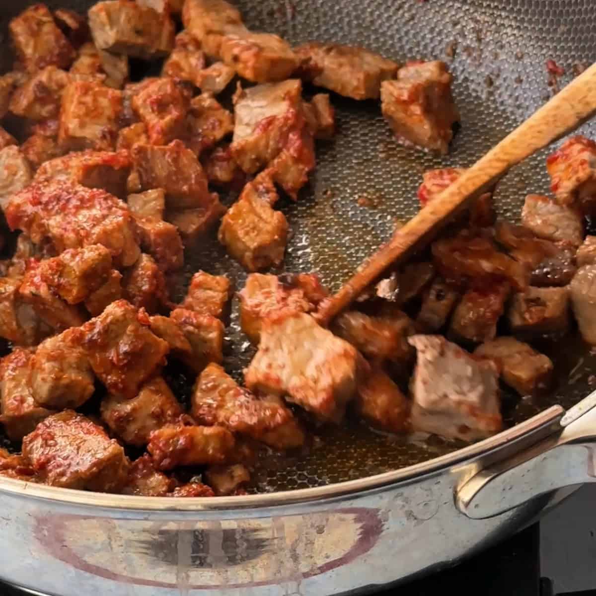 mixing the beef cubes with the tomato paste and spices