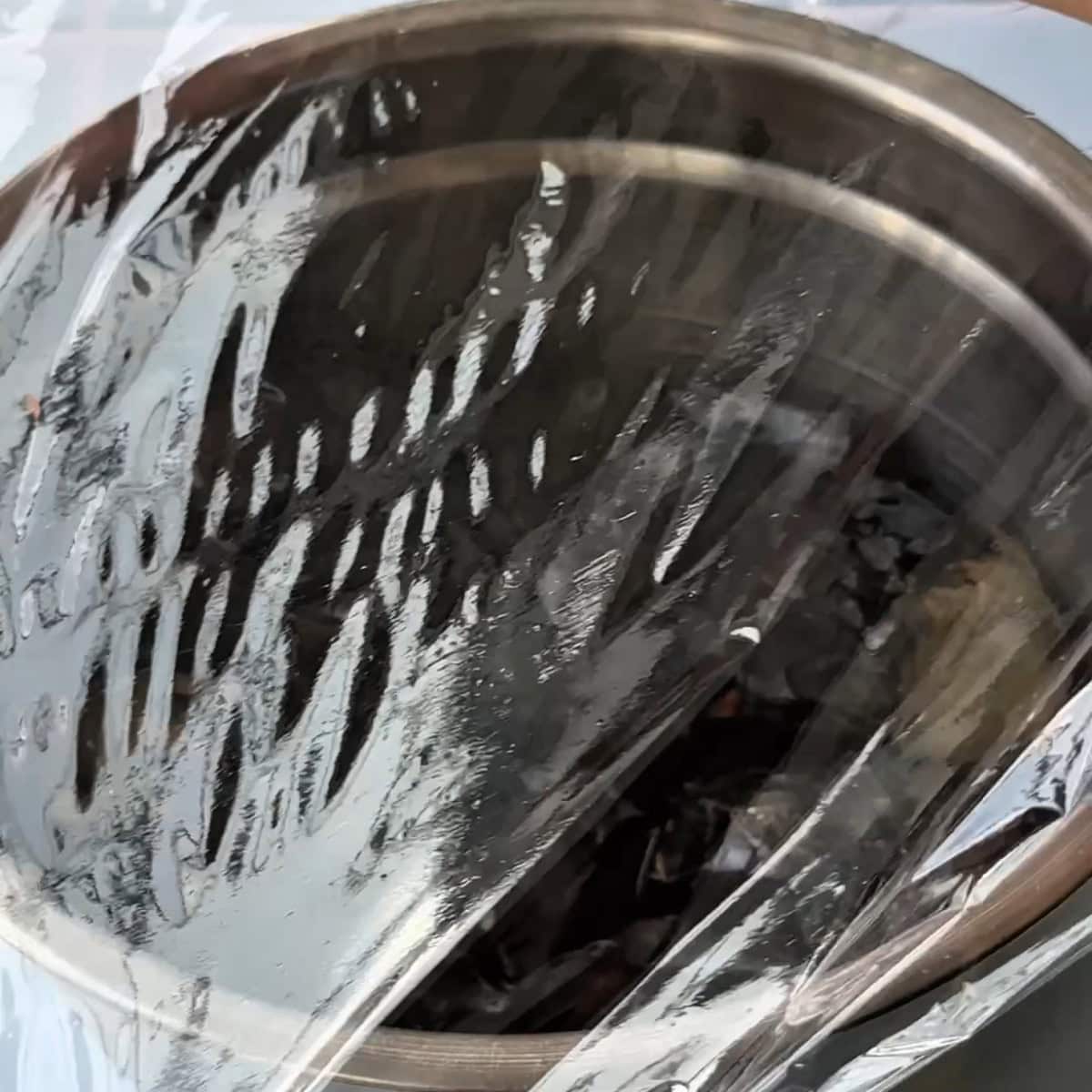 charred eggplant covered with plastic wrap and left to cool down