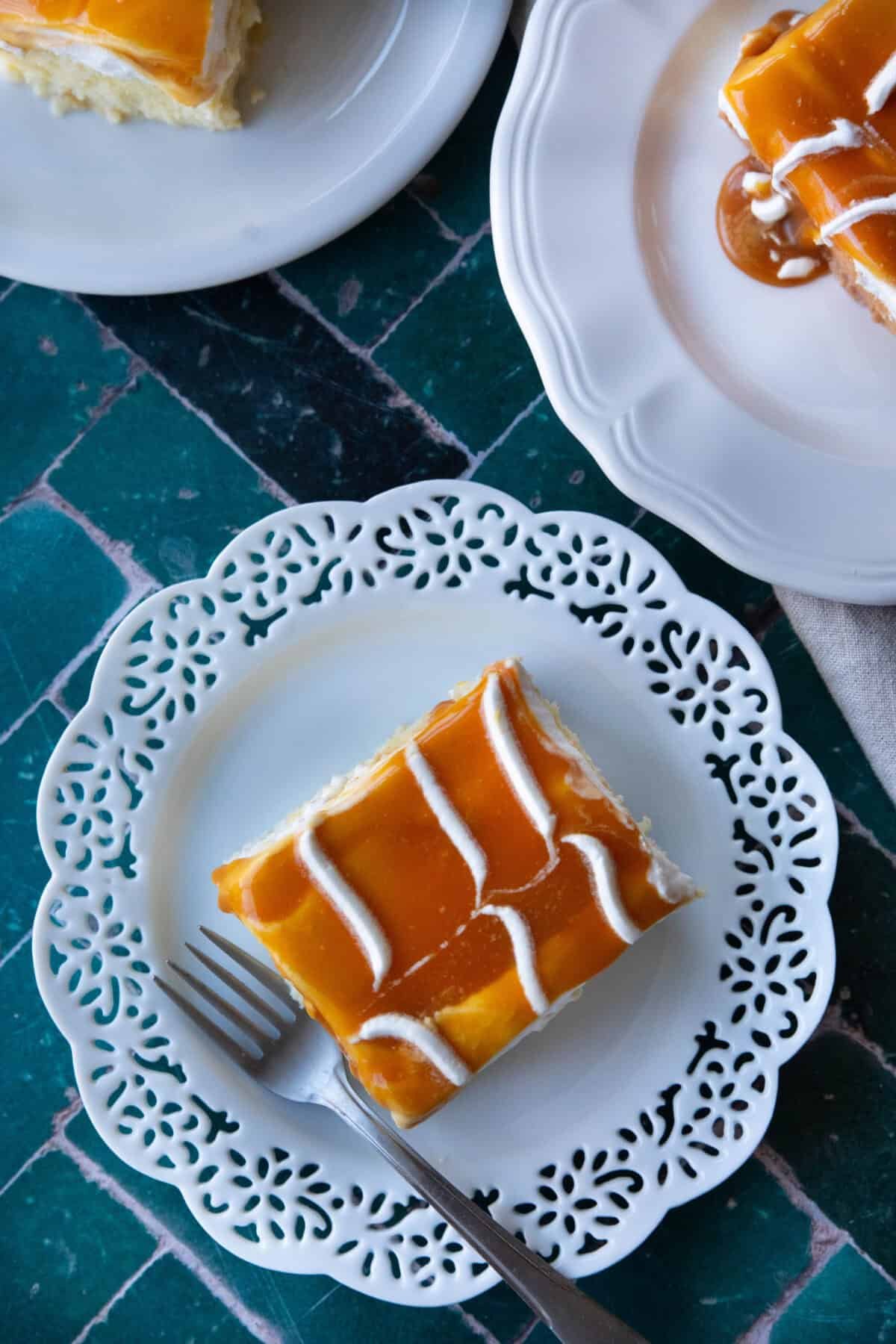 Turkish milk cake (Trilece) on a white plate with soft whipped cream and caramel topping
