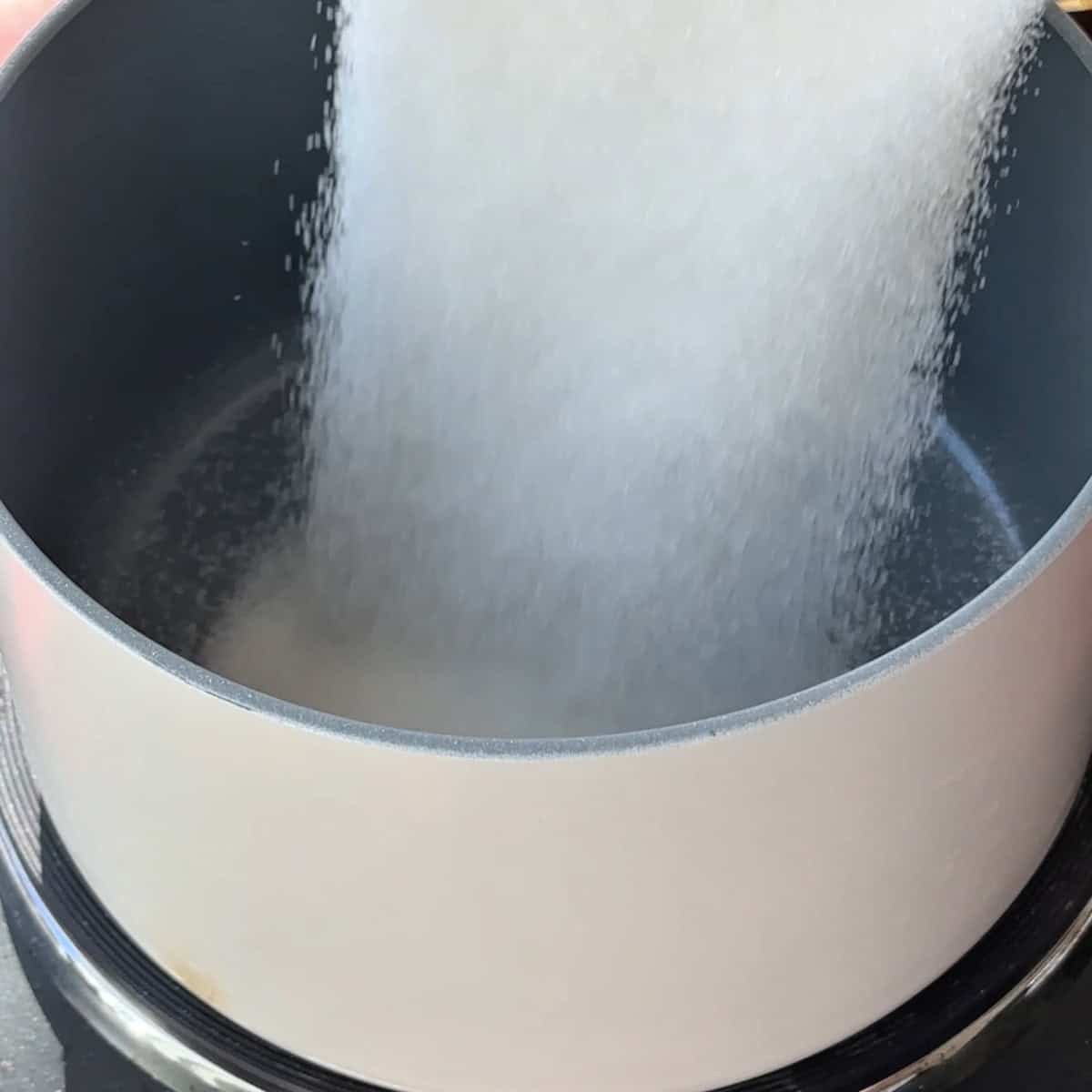adding sugar to the sauce pan to make the caramel sauce for trilece