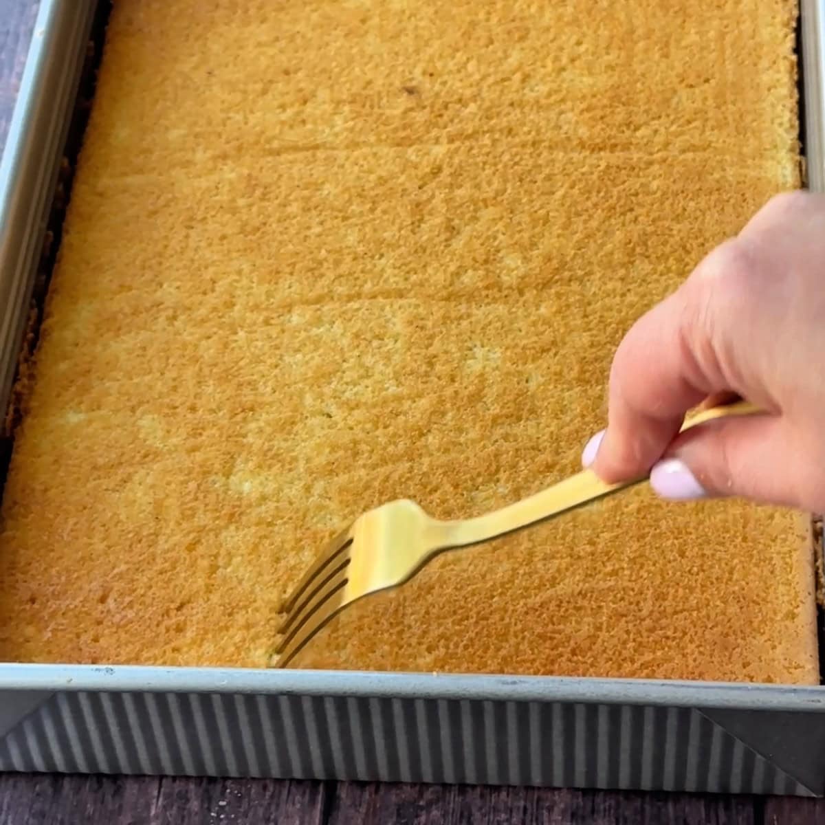 Turkish Milk Cake poking holes in the cake before adding the milk mixture