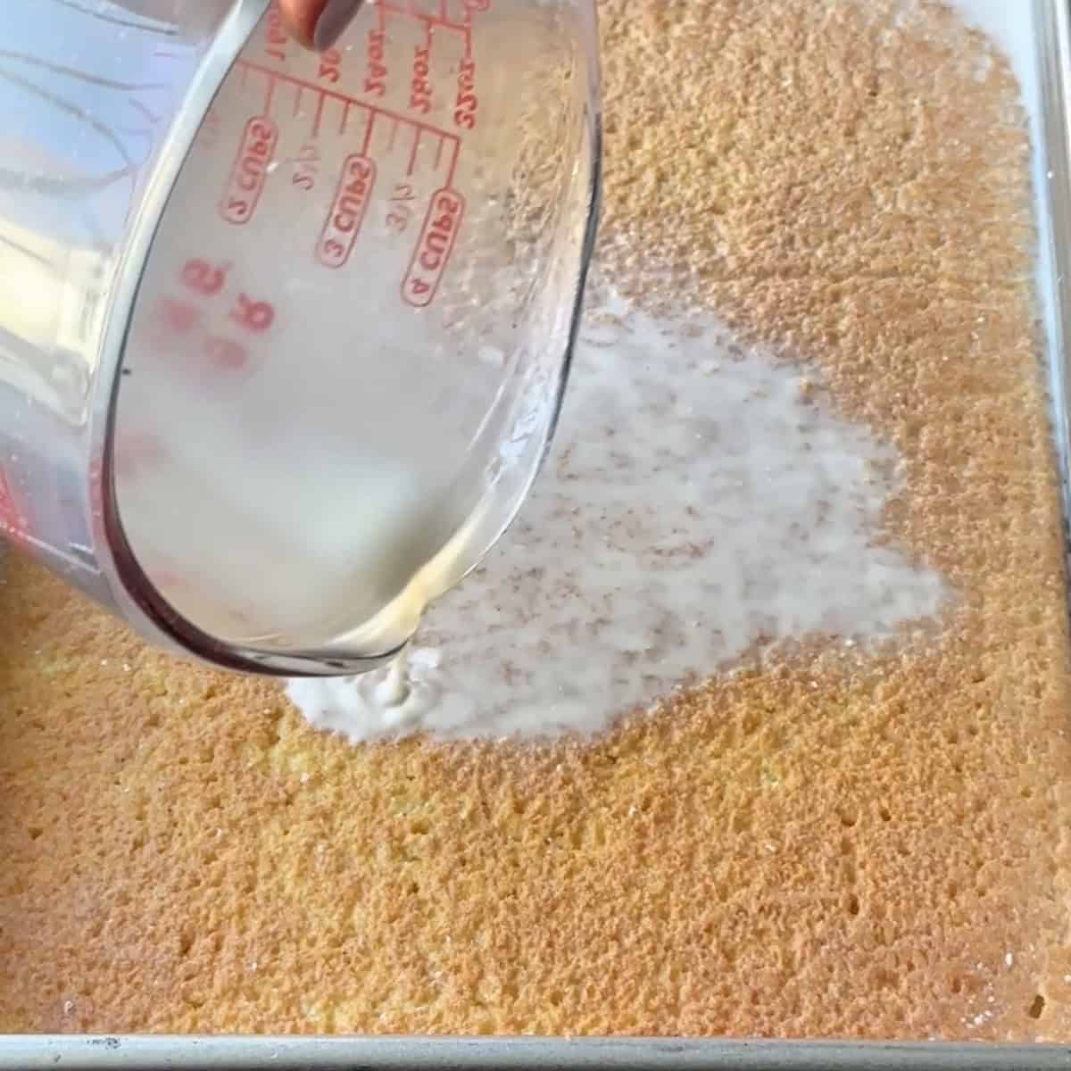 pouring the milk mixture over the sponge cake