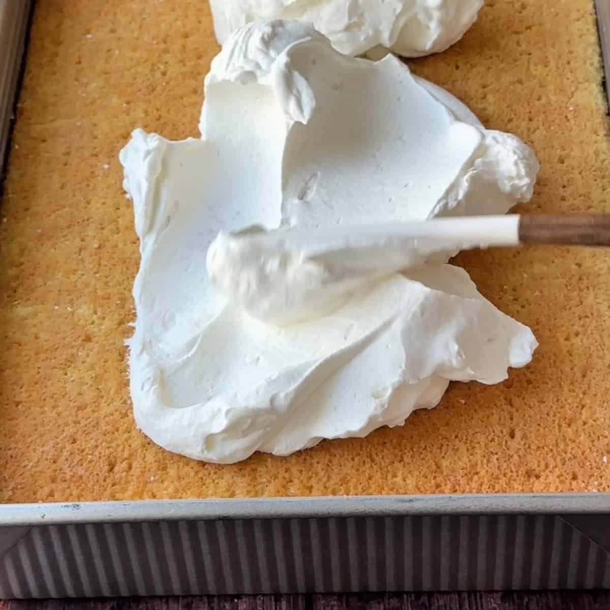 placing the whipped cream layer over the sponge cake soaked with the milk mixture
