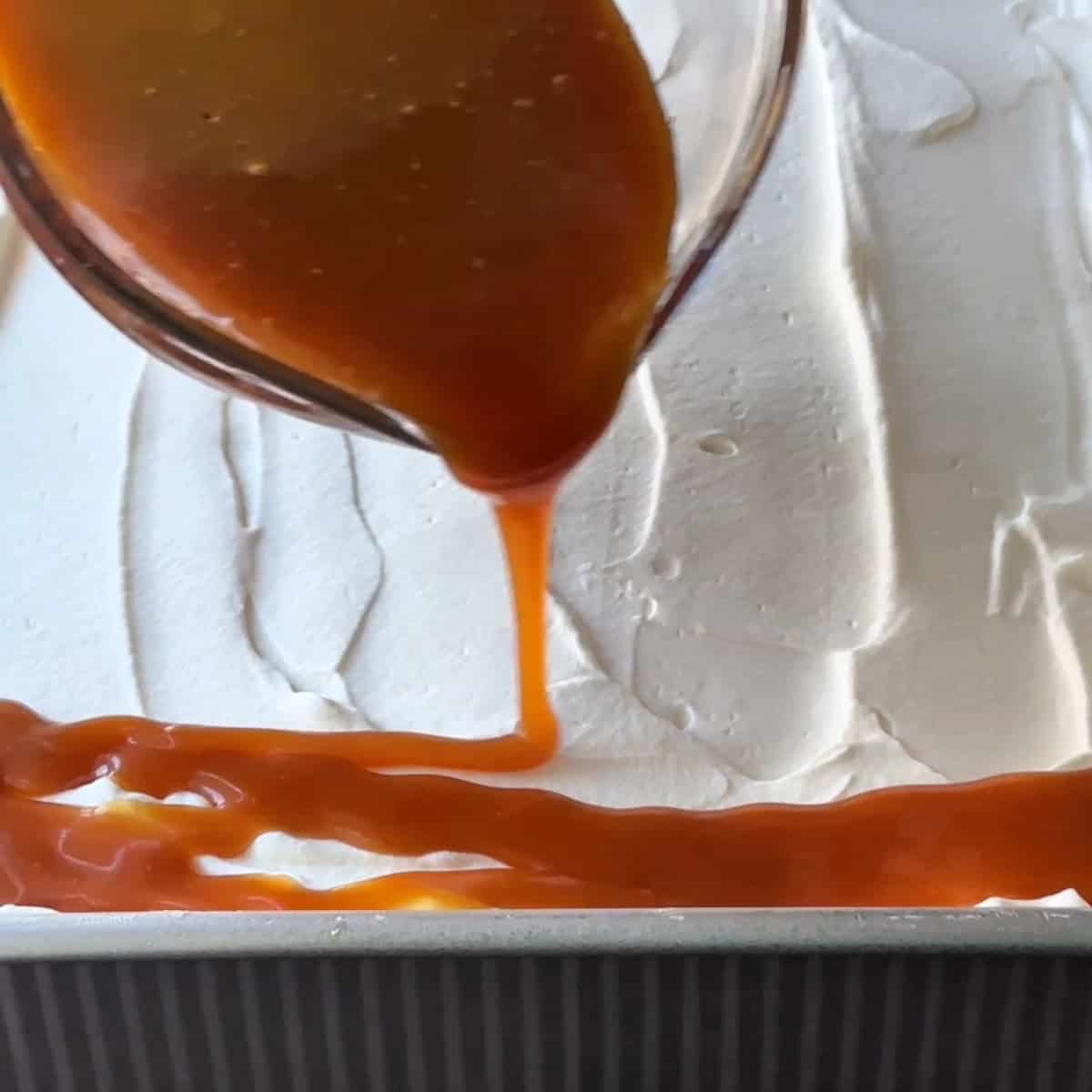 pouring the caramel sauce over the whipped cream layer