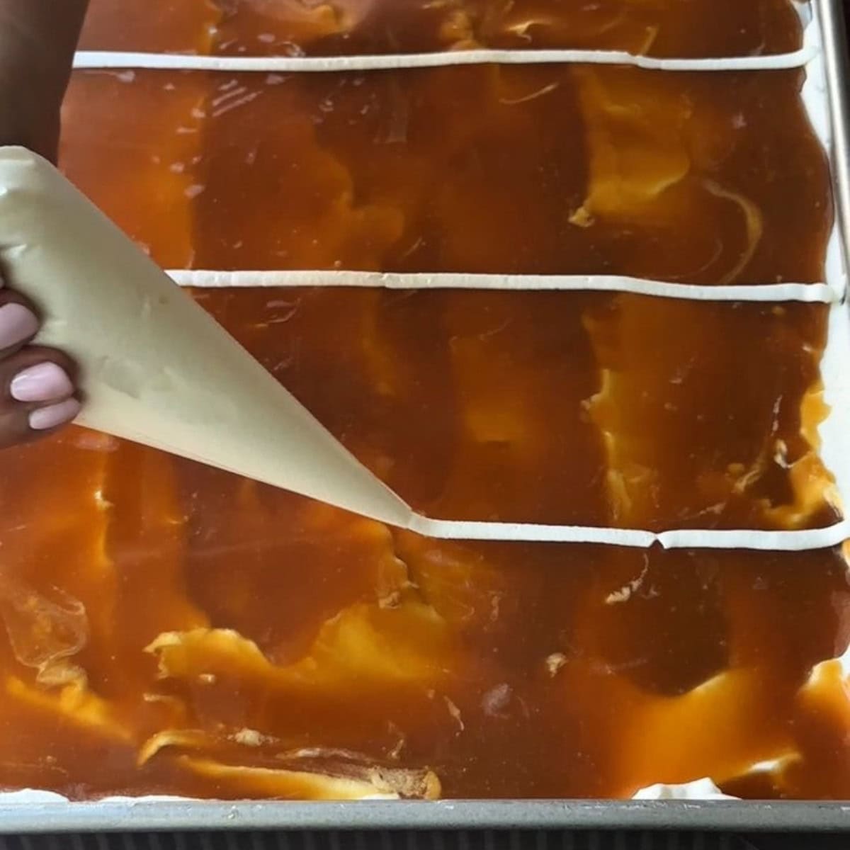 making parallel lines with whipped cream on the caramel layer