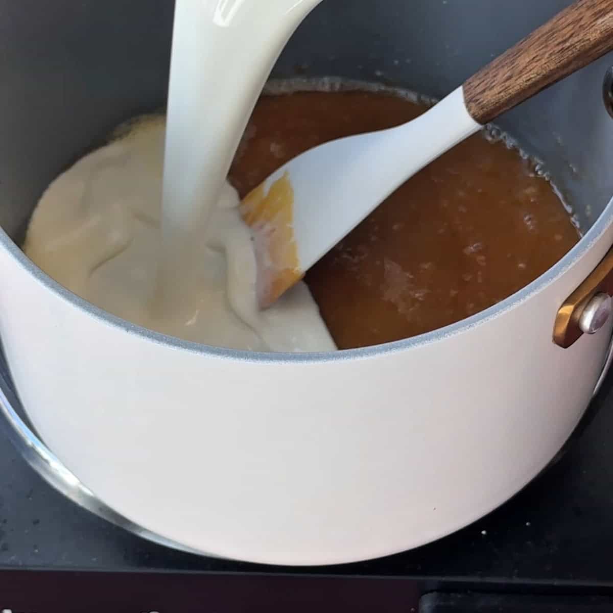 pouring milk over the caramel and butter mixture to make the caramel sauce