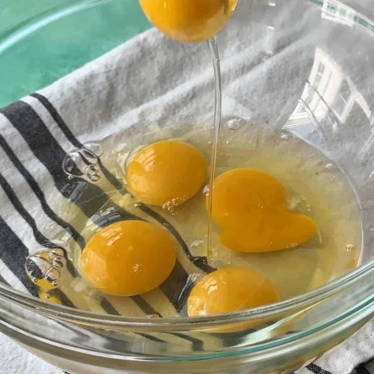 adding eggs to a large bowl to start preparing the cake batter