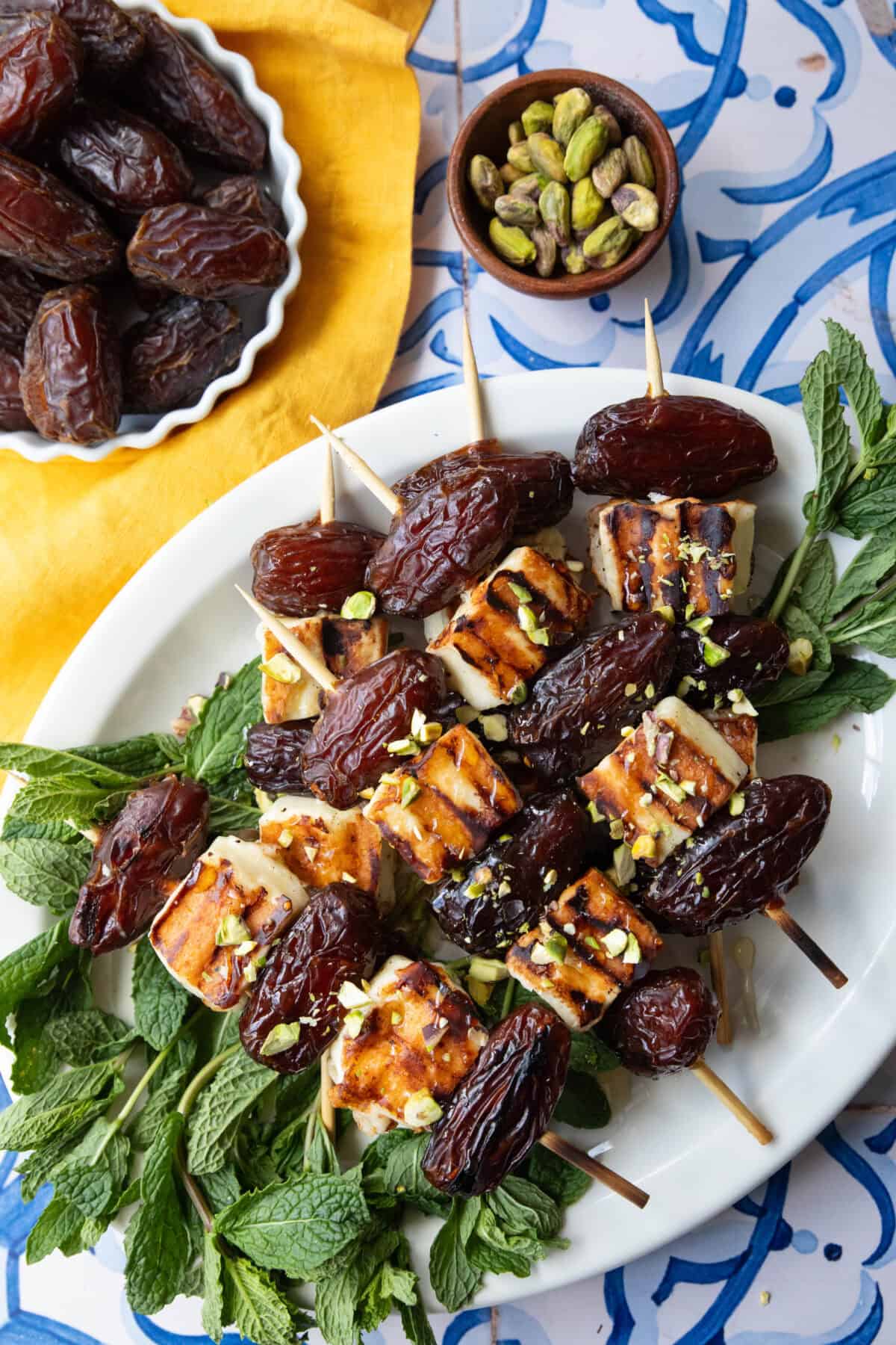 date and halloumi kebabs on a platter with mint.