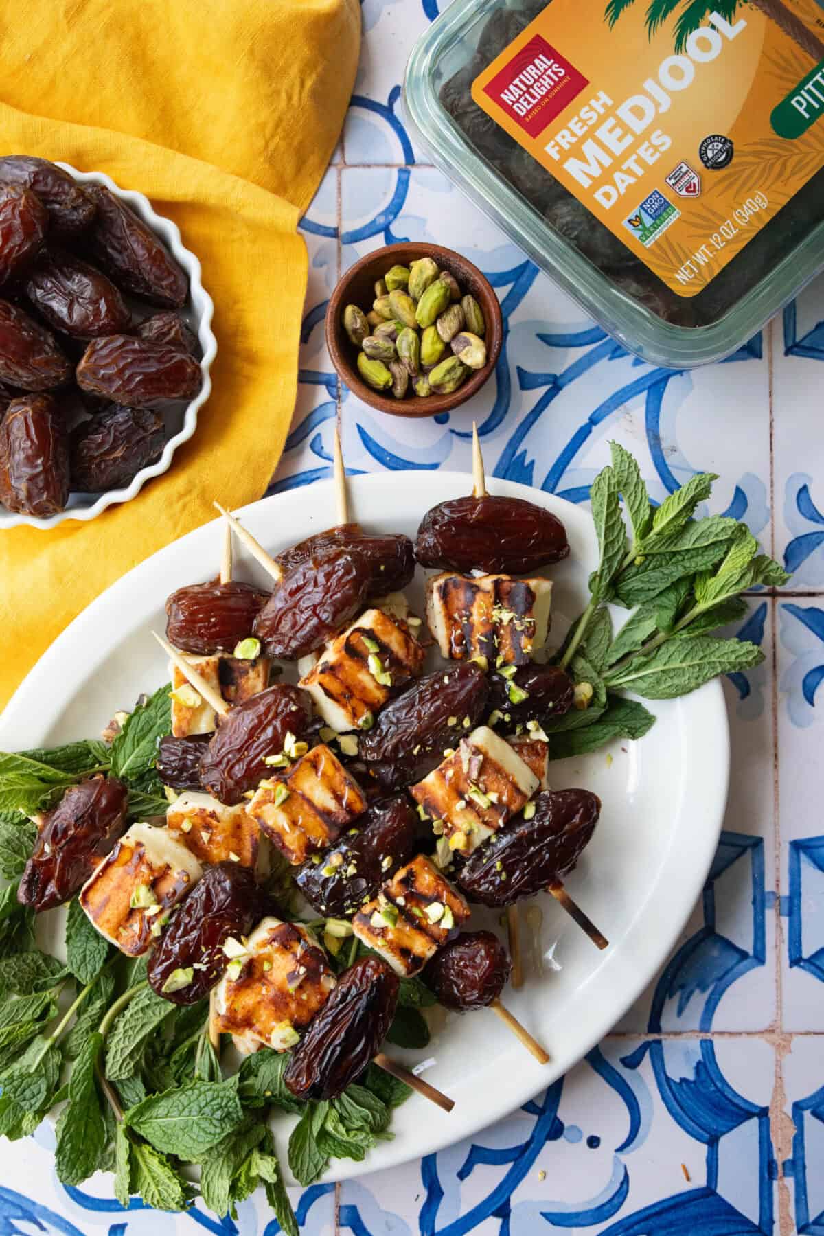 A platter of halloumi date skewers on a white and blue backdrop.