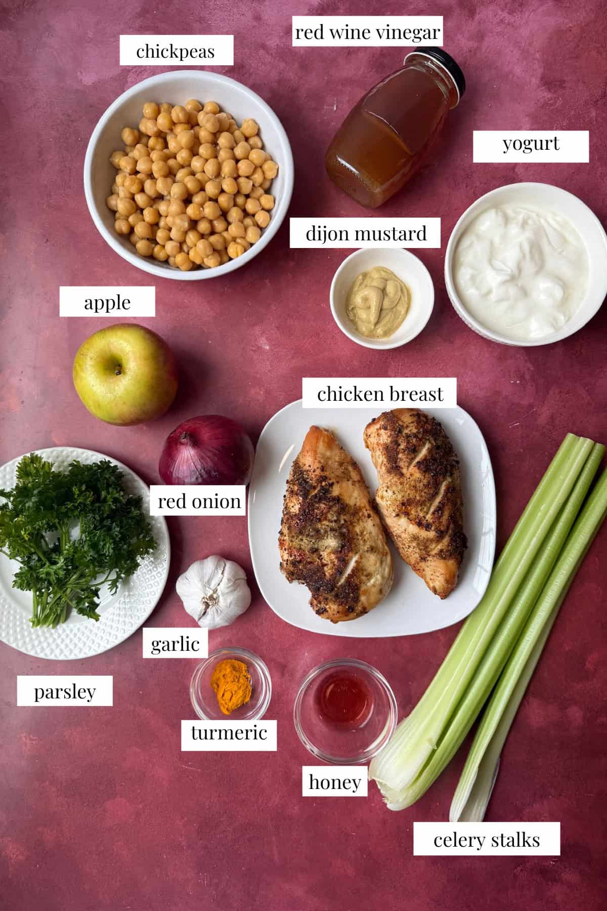Ingredients to make chicken chickpea salad are chicken, chickpeas, celery, parsley, red onion, apple, honey, mustard, yogurt and turmeric.