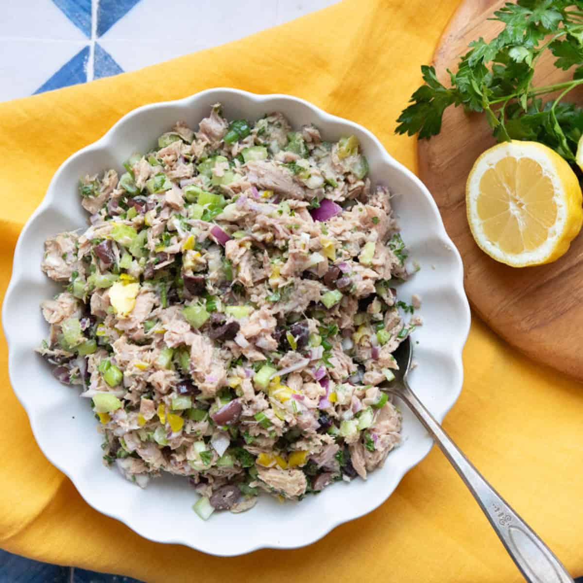 Mediterranean tuna salad in white bowl on a yellow linen. 