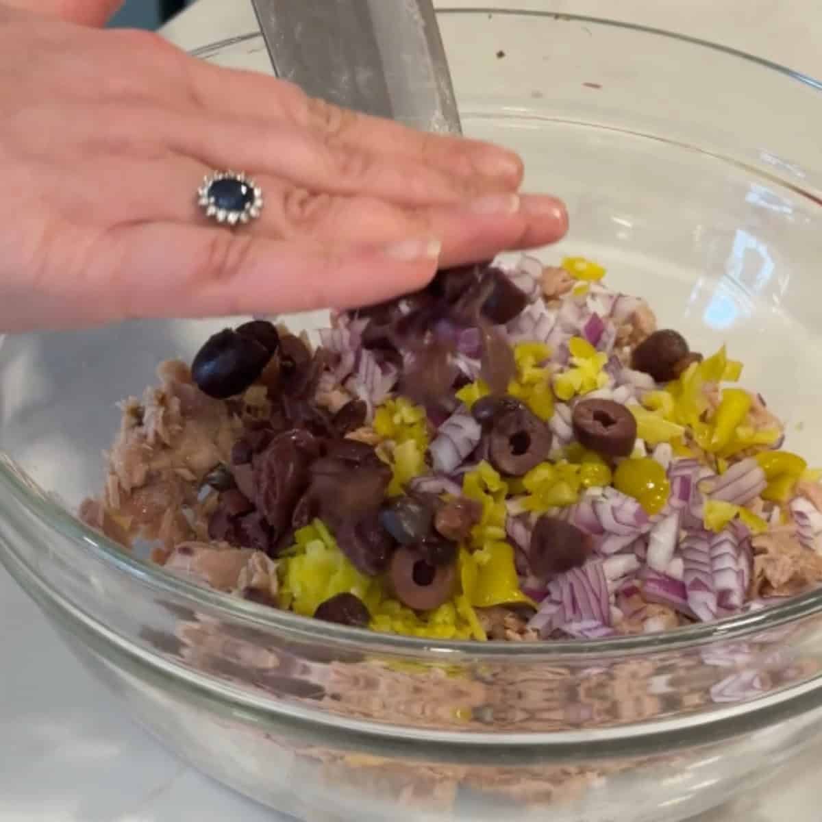 Add the olives and pepperoncini to tuna.