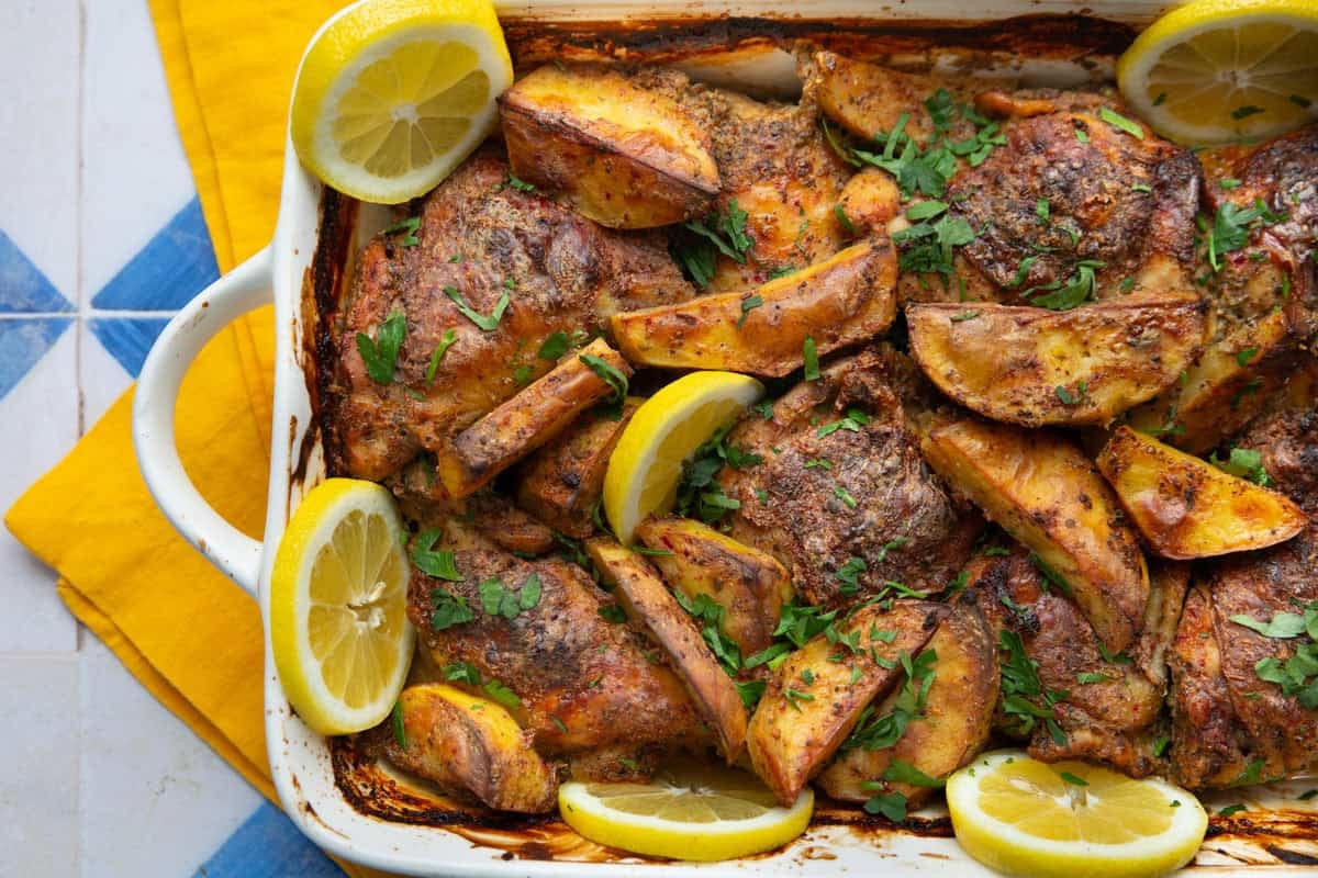 yogurt marinated chicken and potatoes in a baking dish.
