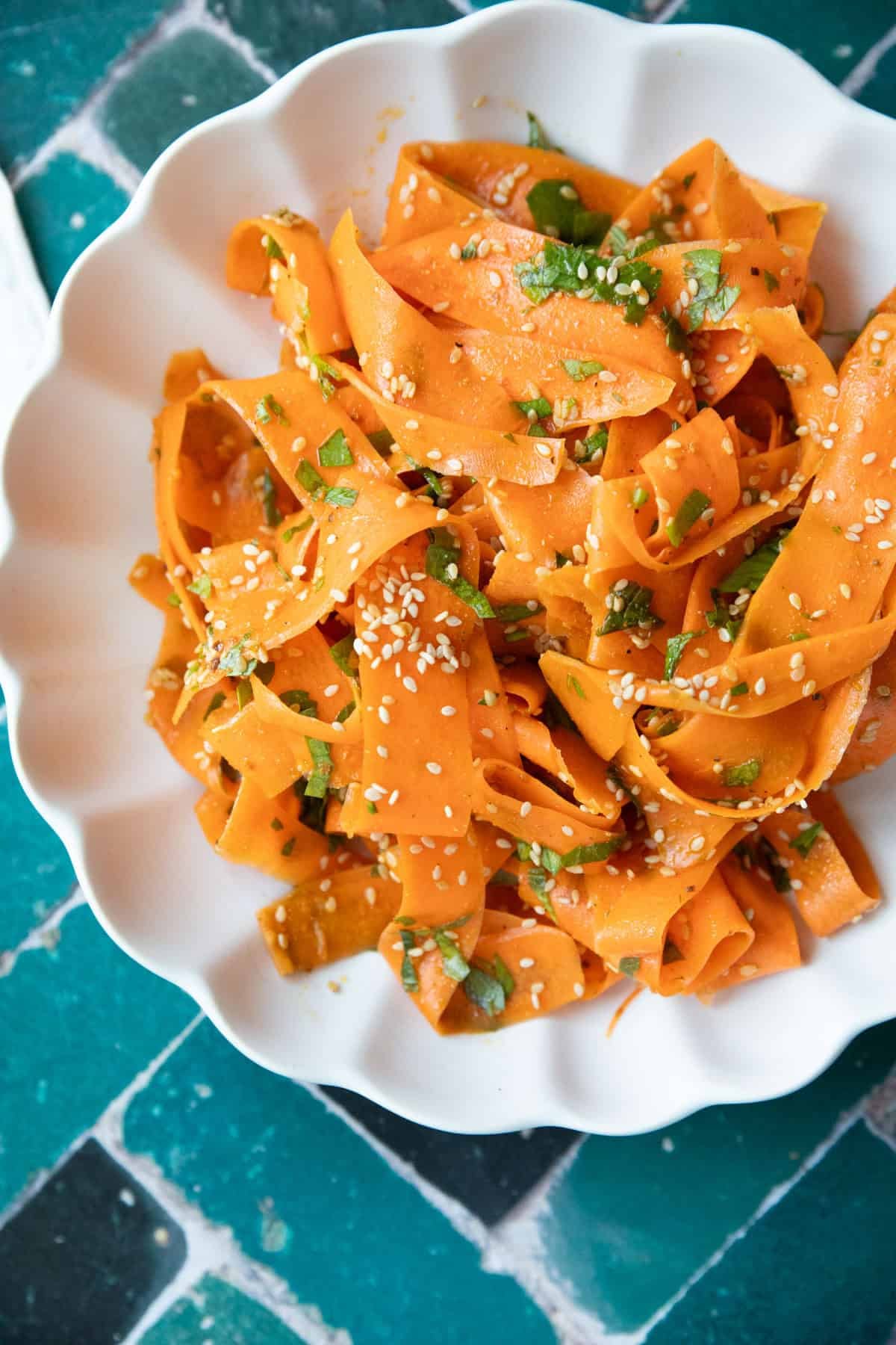 A bowl of ribbon carrot salad topped with sesame seeds and parsley.