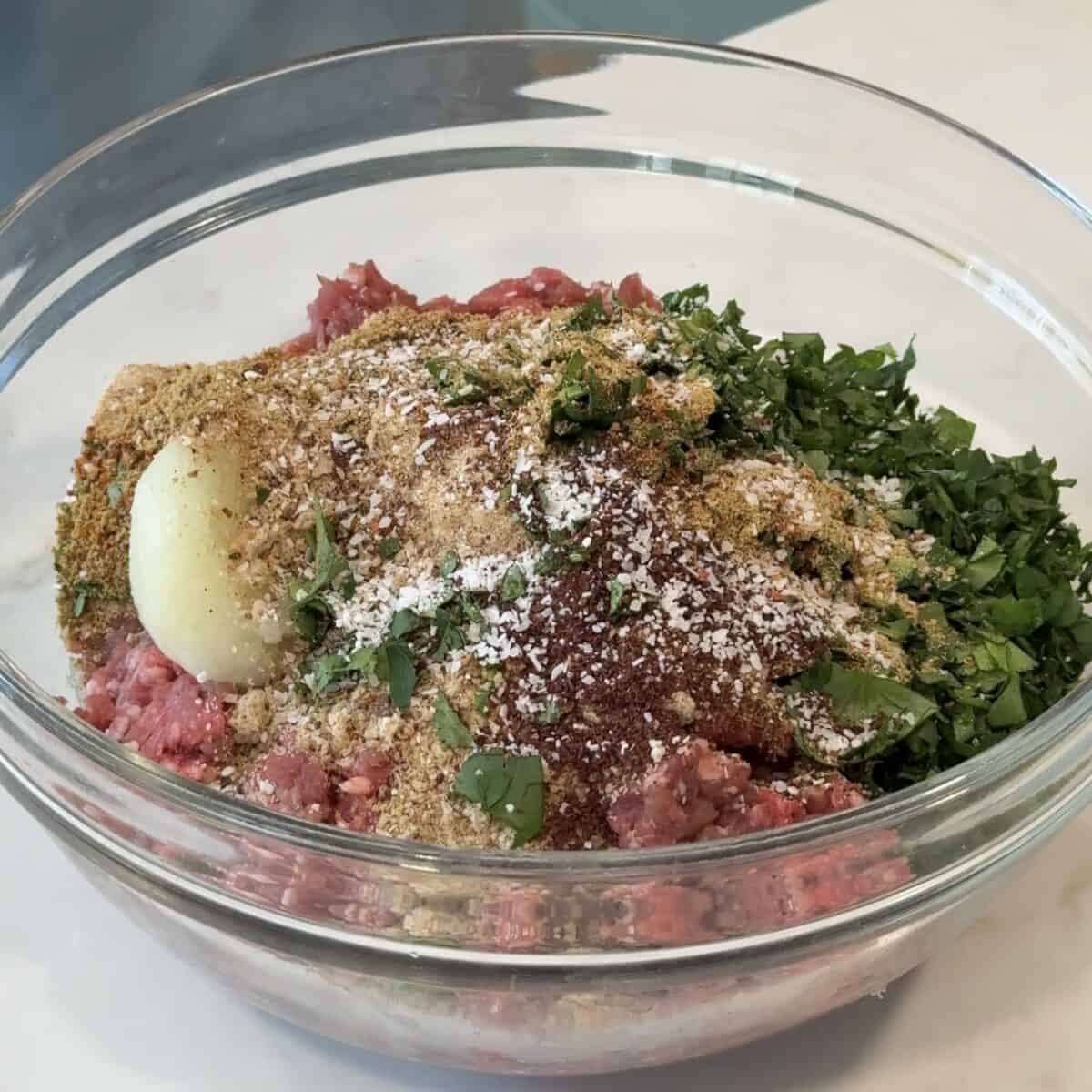 place the ground lamb, spices, herbs, breadcrumbs and onions in a bowl.