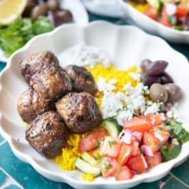 lamb meatballs in a bowl with salad and rice.