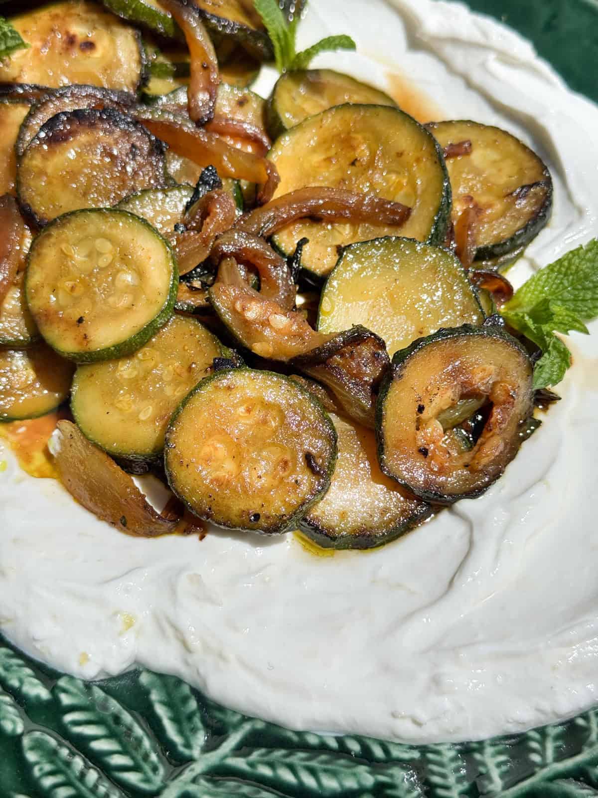 Front shot of sliced zucchini on a platter with yogurt.