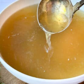 homemade chicken stock from scratch with a ladle.