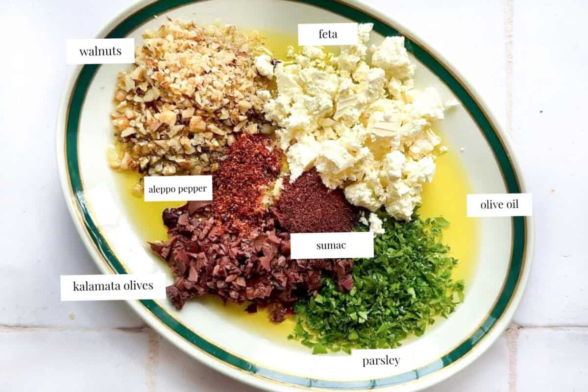 feta, olive oil, sumac, aleppo pepper, walnut and olives on a platter.