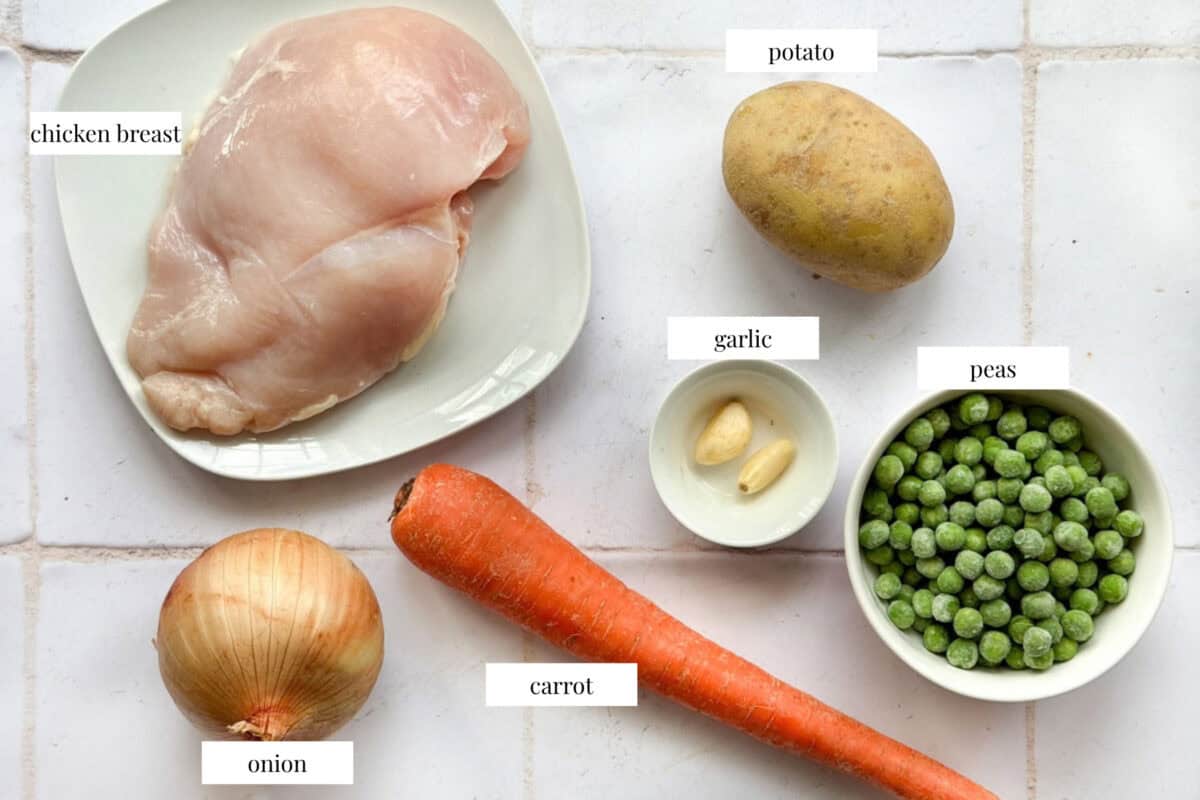 ingredients for comfort chicken soup, chicken, onion, garlic, potatoes, carrots and peas. 