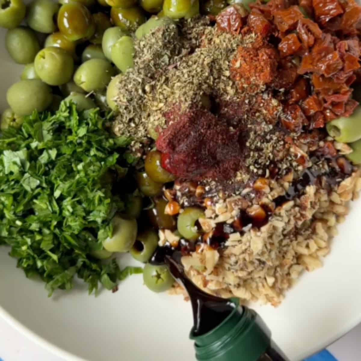 Add sun-dried tomatoes, walnuts, parsley, tomato paste, spices and pomegranate molasses to the olives.