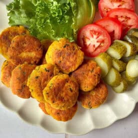 chicken patties on a plate with pickles and tomatoes and pickles.